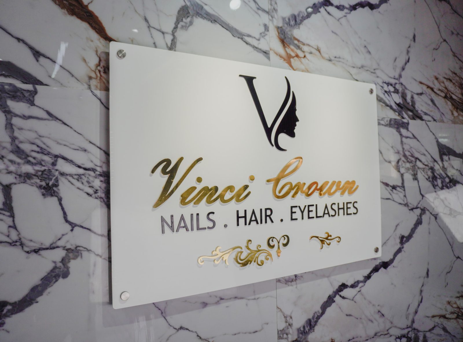 Vinci Crown Nails Hair Eyelashes signage on a marble wall